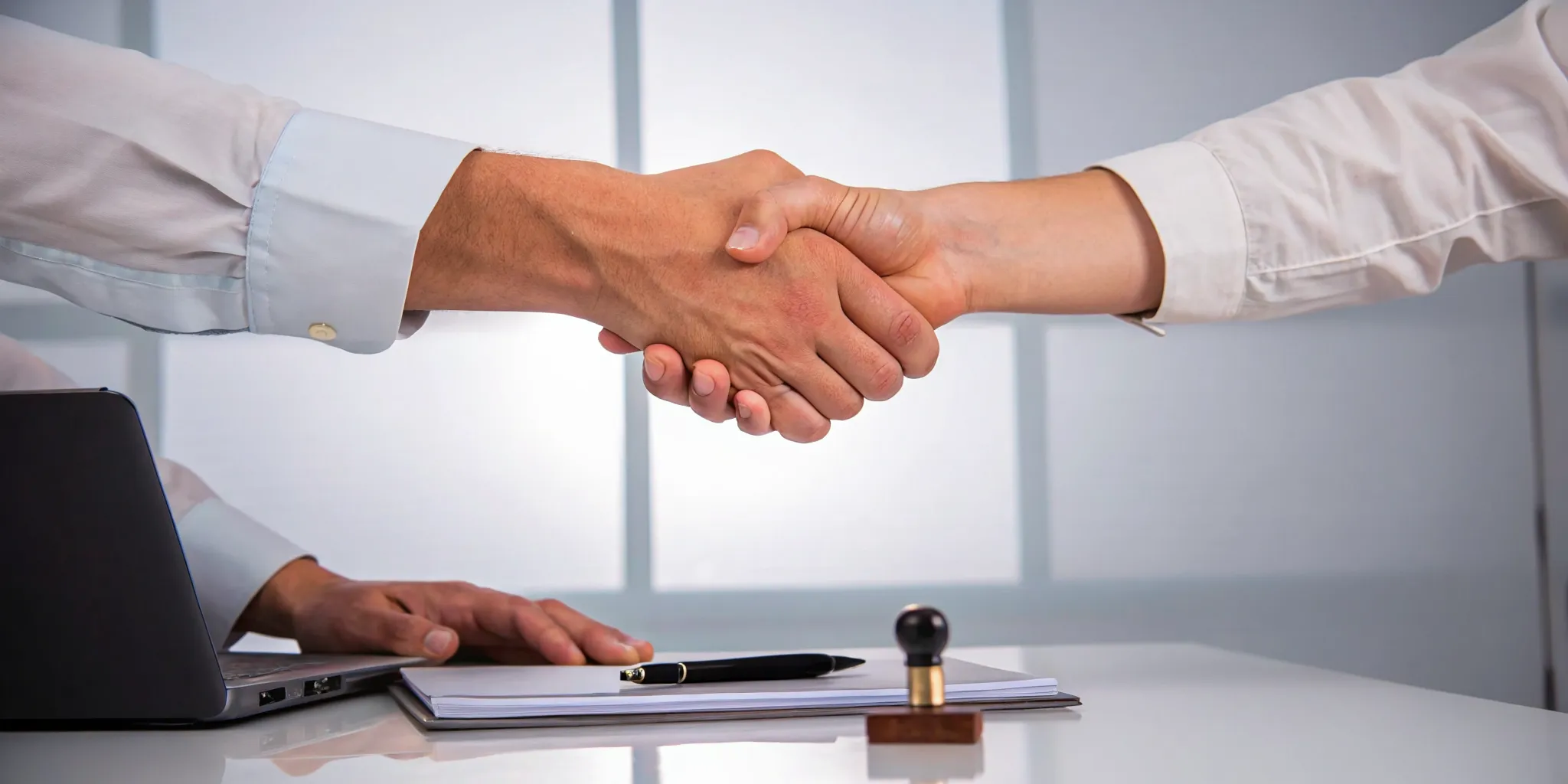 A handshake finalizing a VA claim appeal over a desk with paperwork.